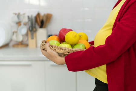 A pregnant woman in kitchen Preparing food for family and unborn children.の写真素材