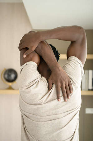 Young African man doing yoga exercise in the living room of his homewith the pleasure of relaxing with light sports In the morning atmosphere of the day.の写真素材