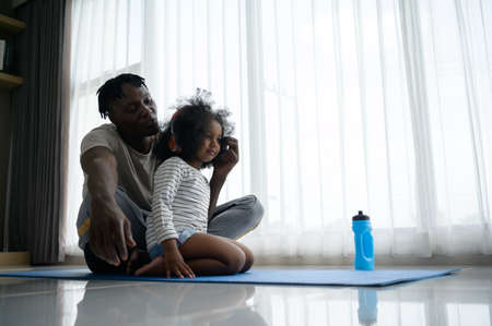 Asian-African American father and son relaxing and listening to music together after yoga exercise in the living room of the house.の写真素材