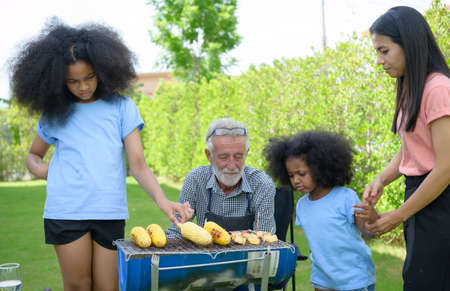 Family holiday activities with grandfather, mother and children with camping. bbq grill and play in the yard together happily on vacation.の写真素材