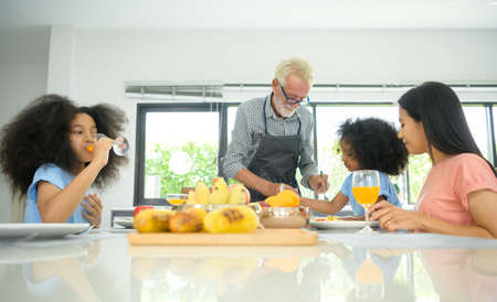 Asian-African American family Have a happy meal together which includes grandfather, mother and children in the dining room of the house.の写真素材