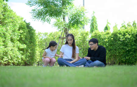 Asian family with both father, mother and daughter having fun in the garden of the house happilyの写真素材