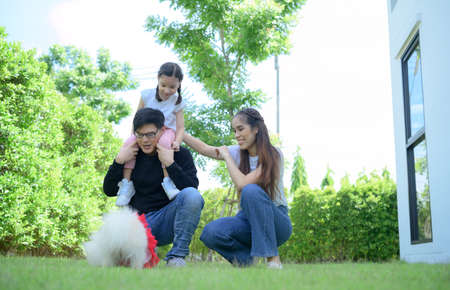 Asian family with both father, mother and daughter having fun in the garden of the house happilyの写真素材