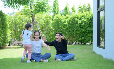 Asian family with both father, mother and daughter having fun in the garden of the house happilyの写真素材