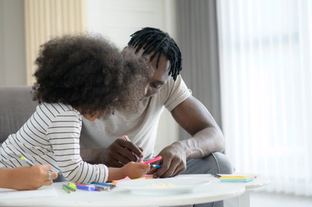 Asian-African American family relaxing, chatting, painting and having fun on vacation in the living room of the houseの写真素材