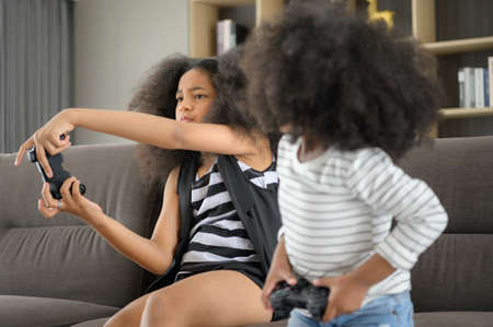 Two brothers of an Asian-African American family. Relax and play online games in the living room of the house.の写真素材