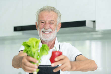 Grandfather is cooking breakfast and prepare food for grandchildren in the kitchen of the house.の写真素材