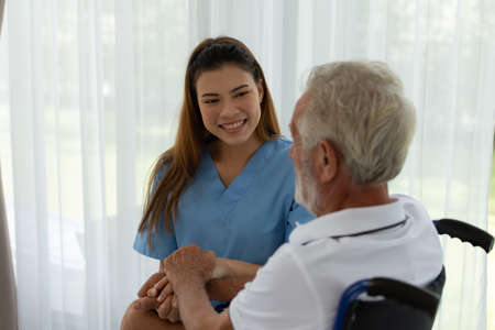 Doctors hold hands and give encouragement to elderly patients who are alone in the hospital's special room.の写真素材