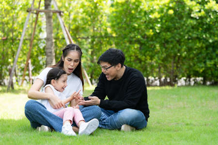 Asian family with both father, mother and daughter having fun in the garden of the house happilyの写真素材
