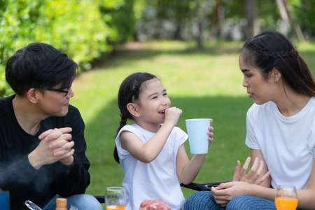 Family holiday activities include father, mother and children with camping barbecue and play in the yard together happily on vacation.の写真素材