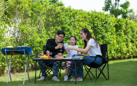 Family holiday activities include father, mother and children with camping barbecue and play in the yard together happily on vacation.の写真素材