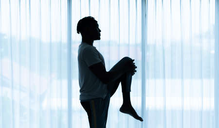 Young African man doing yoga exercise in the living room of his homewith the pleasure of relaxing with light sports In the morning atmosphere of the day.の写真素材