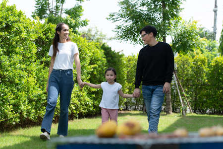 Asian family with both father, mother and daughter having fun in the garden of the house happilyの写真素材
