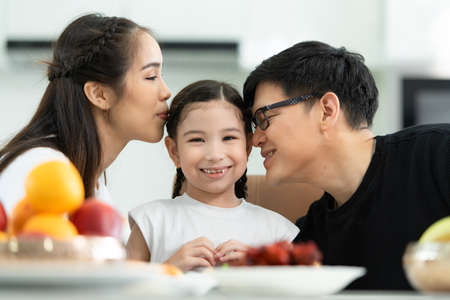 Asian father and mother Show your love to little daughter and having breakfast together happily in the dining room of the house.の写真素材