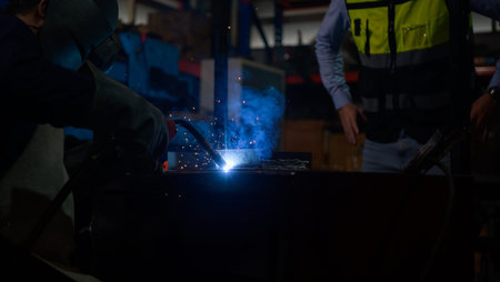 Welder working welding metal with Engineer to closely control the work in order to obtain the...