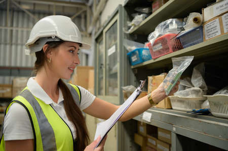 Female warehouse worker Counting items in an industrial warehouse on the factory's mezzanine floor. which is a storage for small and light electronic parts.の写真素材