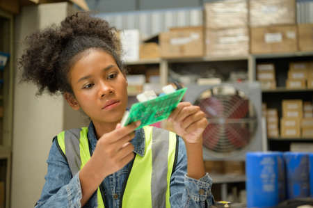 Female warehouse worker Counting items in an industrial warehouse on the factory's mezzanine floor. which is a storage for small and light electronic parts.の写真素材