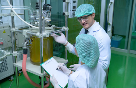 Scientists and assistants are in the machine room extracting oil and cannabis seeds. Inspecting cannabis oil extractor before starting to extract the prepared cannabisの写真素材