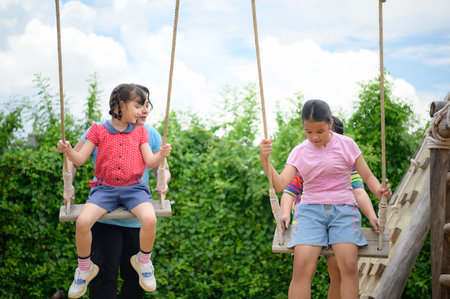 Childrens having fun swinging on a swing on a clear day, the sky is beautifulの写真素材