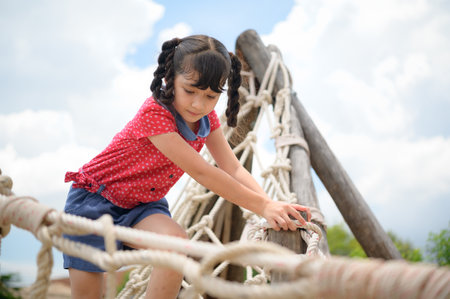 A little girl having fun swinging on a swing on a clear day, the sky is beautifulの写真素材
