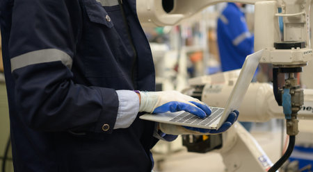 Young male engineers are manipulating a welding robot hand. By combining welding manipulation with a...