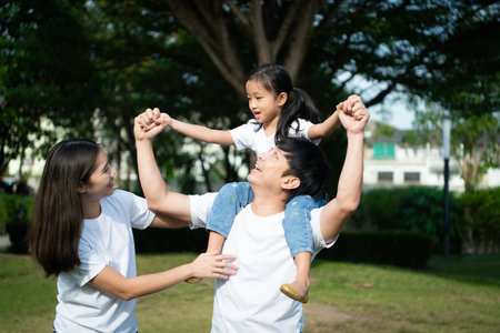 Vacation for a young family Spend this priceless time together playing on the village lawn. The little girl showed her love for her father and mother with kisses on the cheeks or head.の写真素材