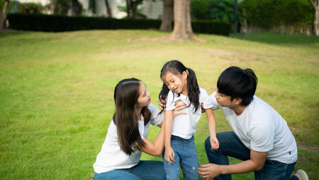 Vacation for a young family Spend this priceless time together playing on the village lawn. A little girl was slightly injured while playing with her parents comforting her at her side.の写真素材