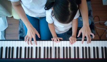 Family vacation, mother helping daughter practice in her piano lessons joyfully and happilyの写真素材