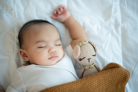 Young mother hugging her newborn child to lull the baby to sleep in the white bedroom, warm sunlight...