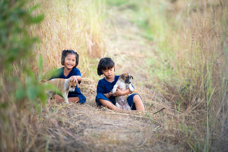In rural Thailand, little girls play together joyfully laugh together and play with the pet dogsの写真素材