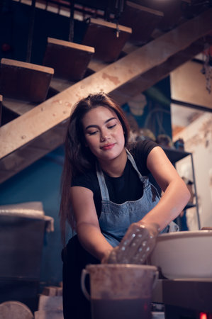 Pottery artist, Young female making a piece of clay molding calmly and meticulously In order to produce the most attractive work possible,の写真素材