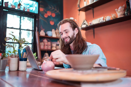 A young businessman owns a small pottery business. Are building themselves by saving money to expand...