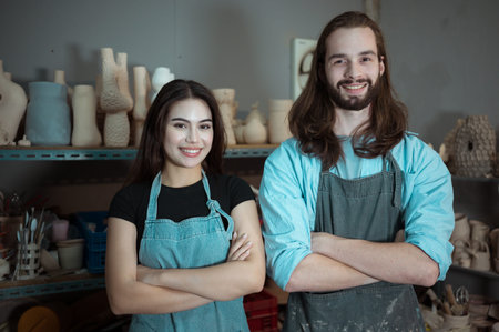Portrait of Young business man and woman having a little ceramic business, with the pottery business and pottery goods in stockの写真素材