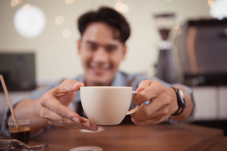 Young barista with the intention of making up a latte coffee to satisfy customers both in appearance and taste, This cup of coffee is ready to be served.の写真素材