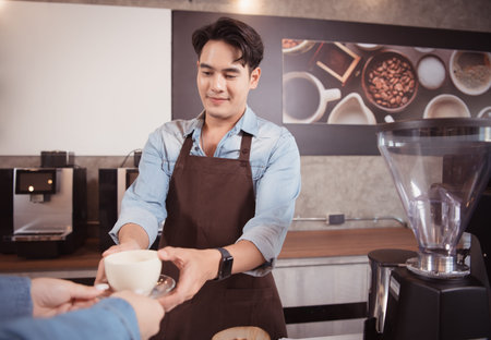Young barista with the intention of making up a latte coffee to satisfy customers both in appearance and taste, This cup of coffee is ready to be served.の写真素材