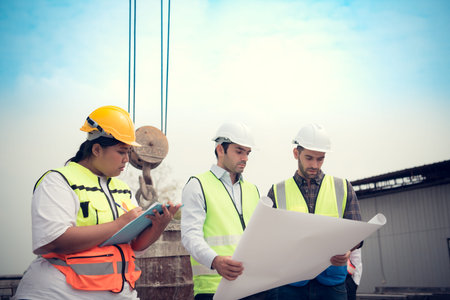 Group of architects, construction foremen, and construction engineers review the work and talk about...