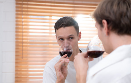 LGBT Young couple celebrate the day of love between each other with fine wine in the kitchen of the...