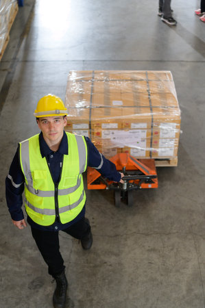 Worker in auto parts warehouse use a handcart to work to bring the box of auto parts into the...