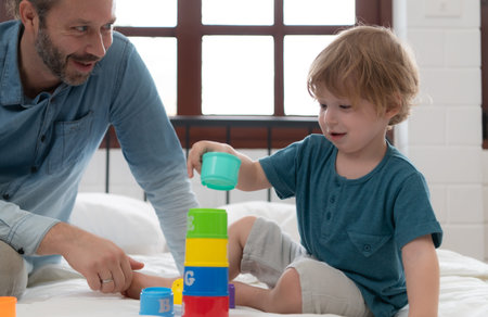 Father with little boy have fun playing with your new toys in the bedroom together. Toys that enhance children's thinking skills.の写真素材