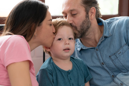 After the little boy wakes up from his nap, his father and mother engage in enjoyable activities in his bedroom.の写真素材