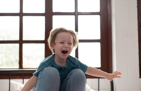 Little boy flying with mom using her legs to help him fly high off the floor of his bed in the bedroom.の写真素材