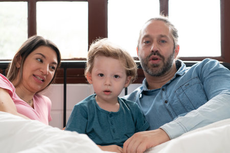 After the little boy wakes up from his nap, his father and mother engage in enjoyable activities in his bedroom.の写真素材