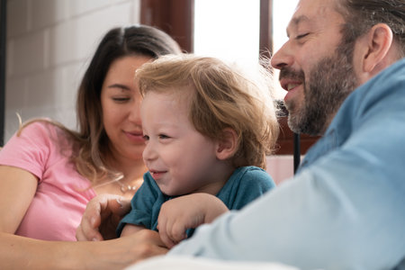 After the little boy wakes up from his nap, his father and mother engage in enjoyable activities in his bedroom.の写真素材