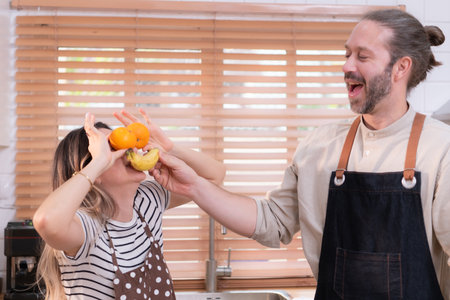 Father and mother in the house's kitchen have a good time making dinner together while awaiting the return of the youngster from schoolの写真素材