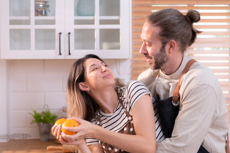 Father and mother in the house's kitchen have a good time making dinner together while awaiting the return of the youngster from schoolの写真素材