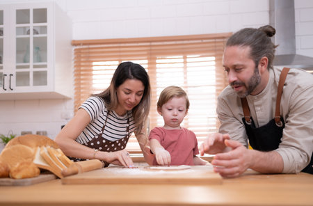 Mom and dad in the kitchen of the house with their small children. Have a good time baking bread and making dinner together.の写真素材