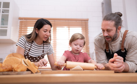 Mom and dad in the kitchen of the house with their small children. Have a good time baking bread and making dinner together.の写真素材