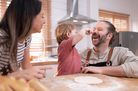 Mom and dad in the kitchen of the house with their small children. Have a good time baking bread and making dinner together.の写真素材