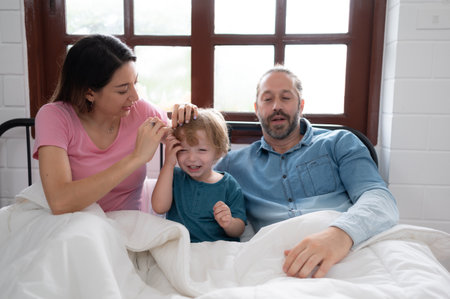 After the little boy wakes up from his nap, his father and mother engage in enjoyable activities in his bedroom.の写真素材