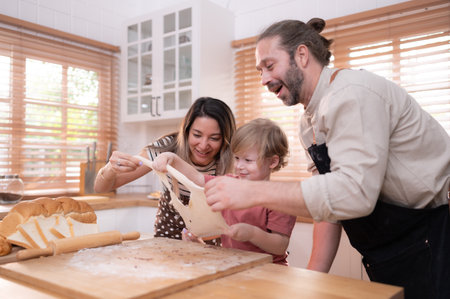 Mom and dad in the kitchen of the house with their small children. Have a good time baking bread and making dinner together.の写真素材